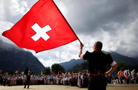 A boy dressed in traditional a costume waves a Swiss flag during the official ceremonial act at the 28th Federal Yodelling Festival in Interlaken